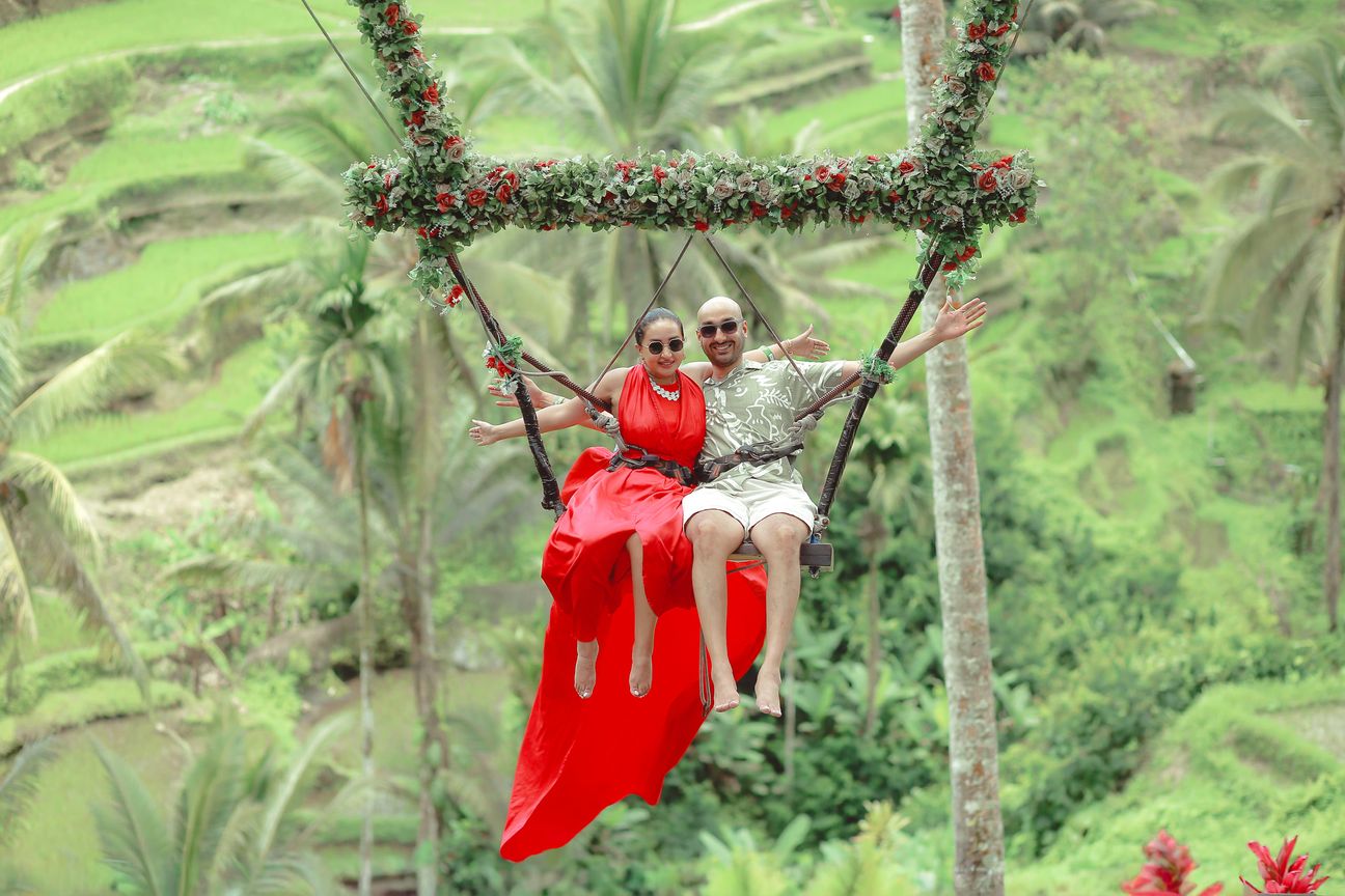 A couple share a swing above green rice terraces in Bali