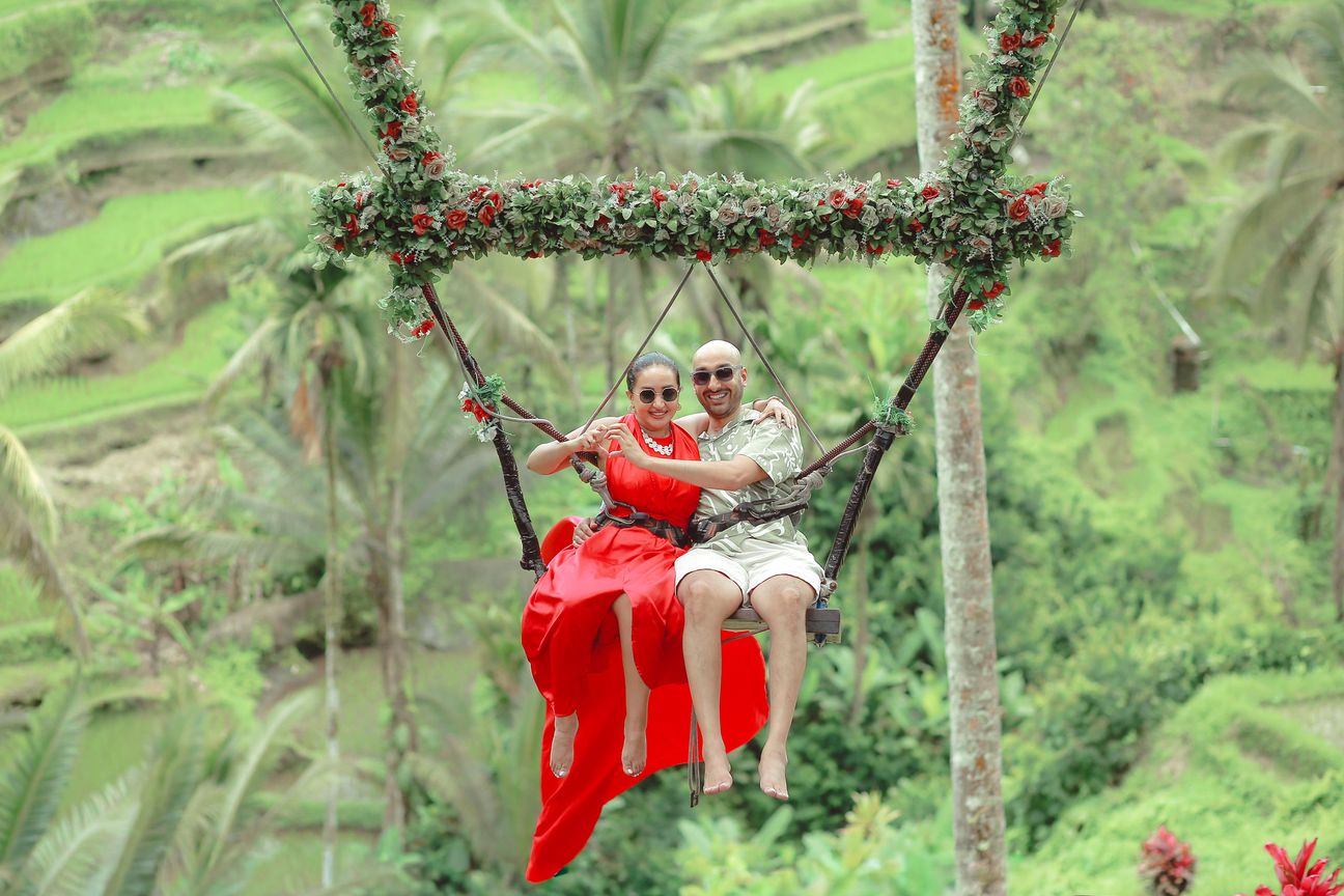 A couple share a swing above green rice terraces in Bali