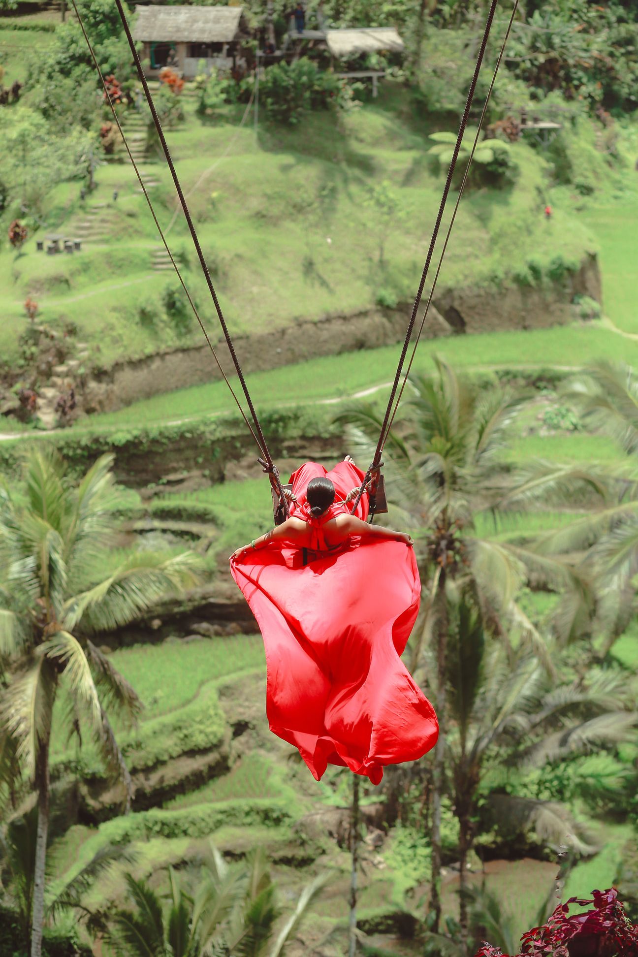 A couple share a swing above green rice terraces in Bali