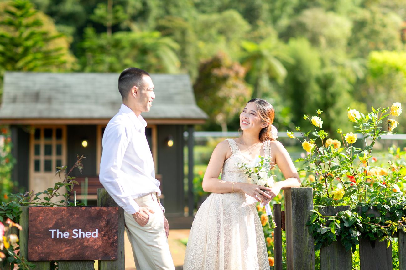 A couple share a laugh by a wooden garden fence surrounded by yellow blooms
