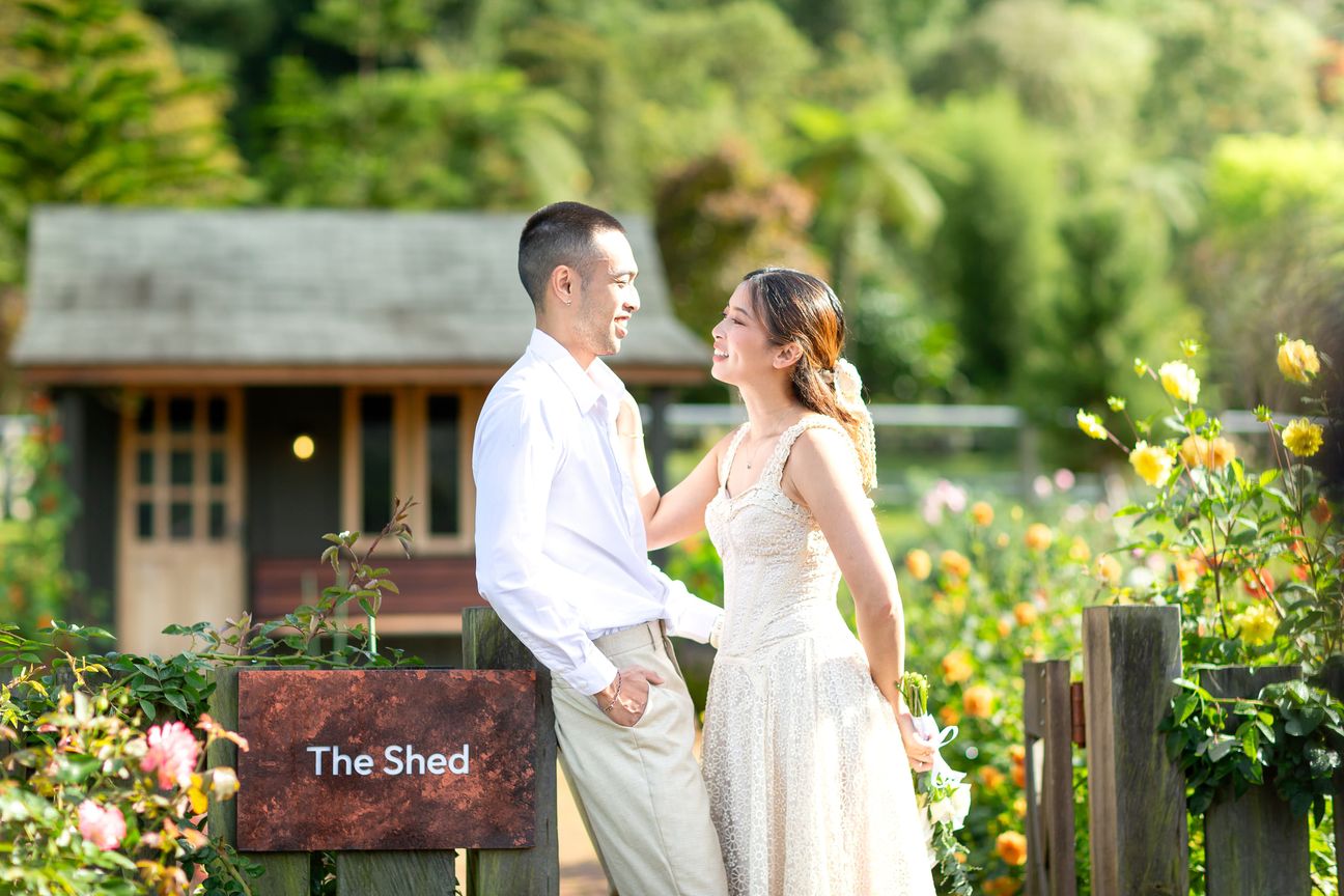 A couple share a laugh by a wooden garden fence surrounded by yellow blooms