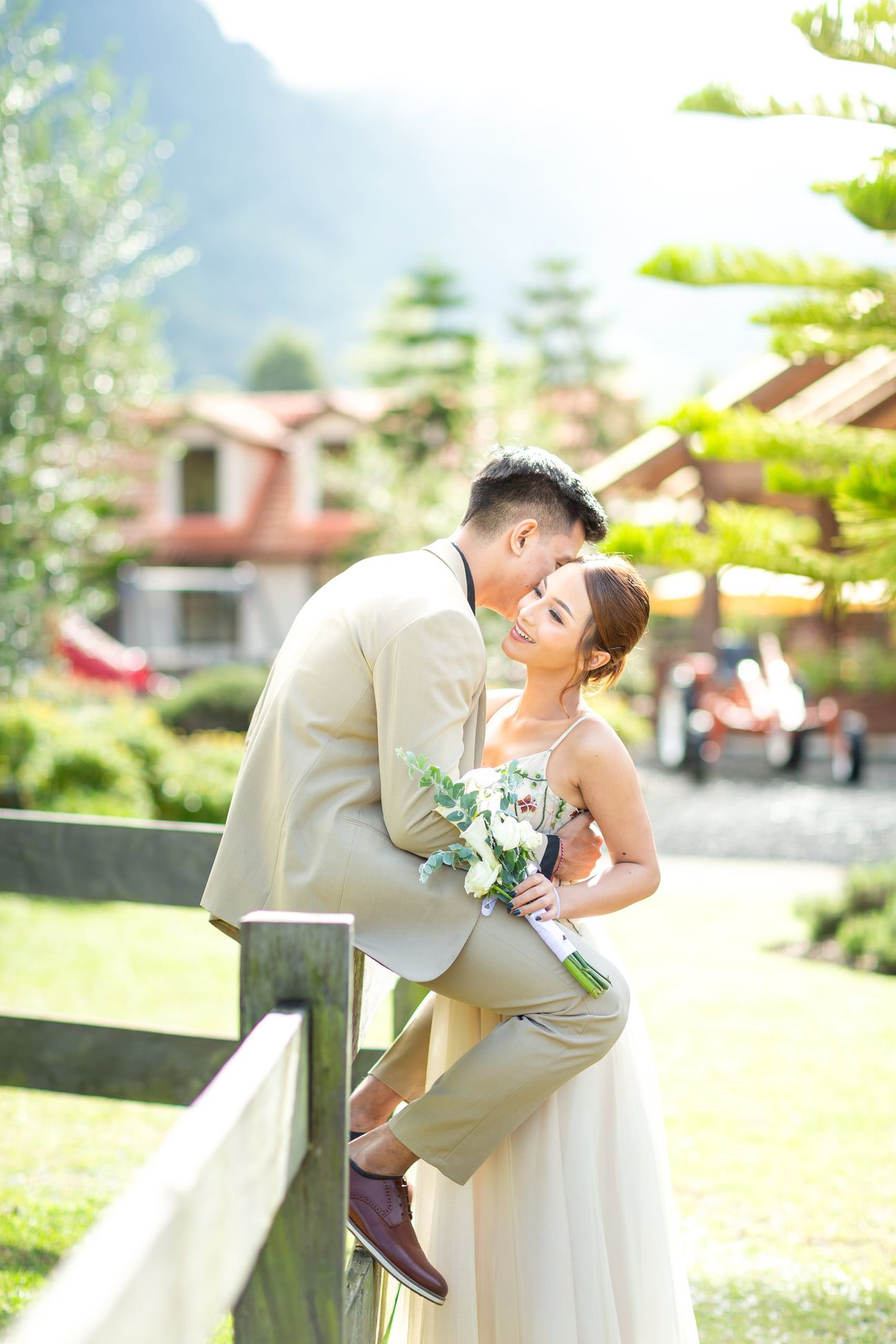 A couple share a laugh by a wooden garden fence surrounded by yellow blooms