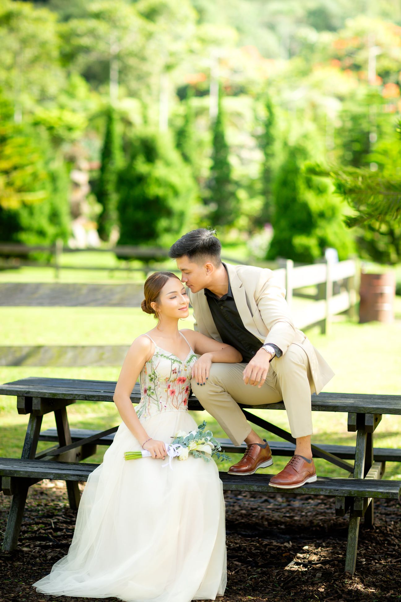 A couple share a laugh by a wooden garden fence surrounded by yellow blooms
