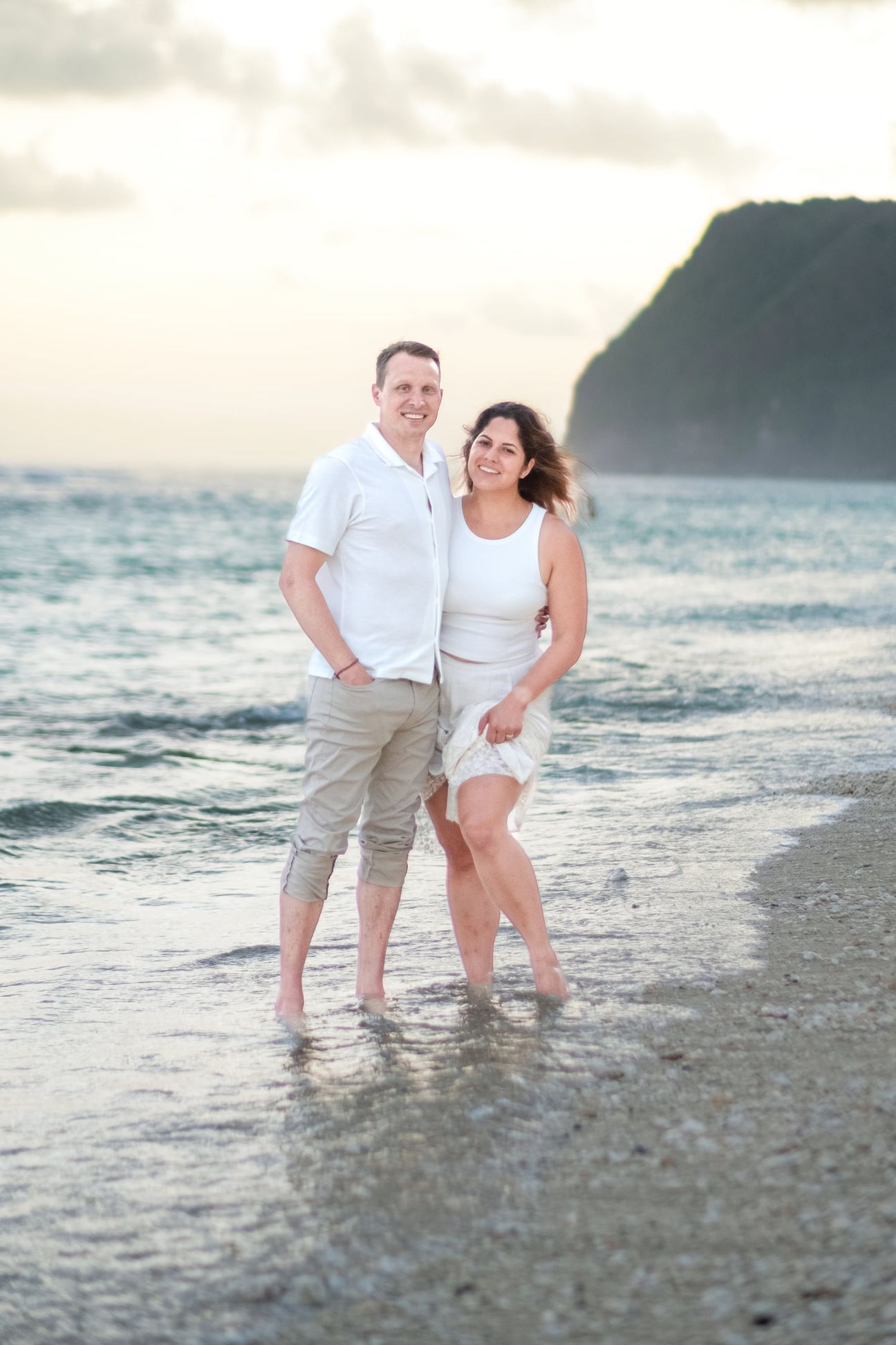 A couple embrace and walk together on a beach near sunset