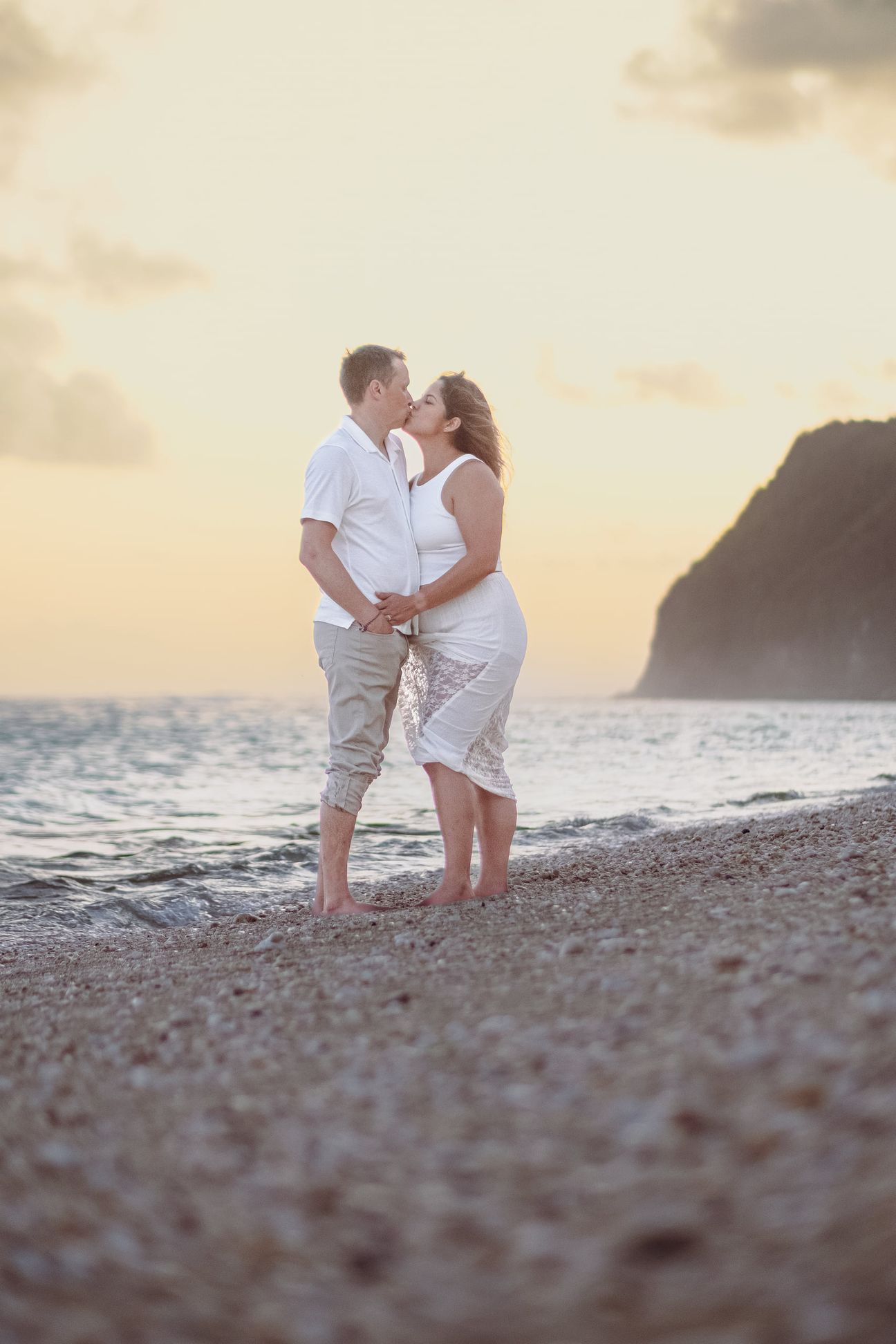 A couple embrace and walk together on a beach near sunset