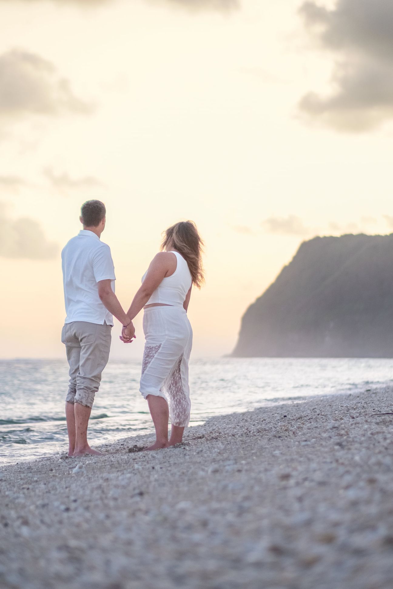 A couple embrace and walk together on a beach near sunset