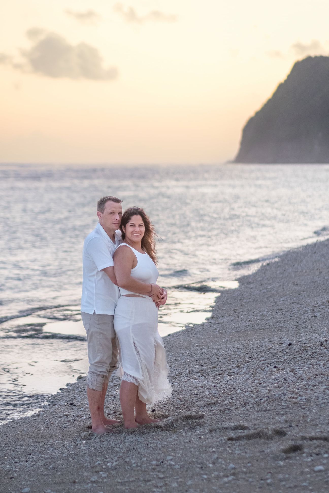 A couple embrace and walk together on a beach near sunset