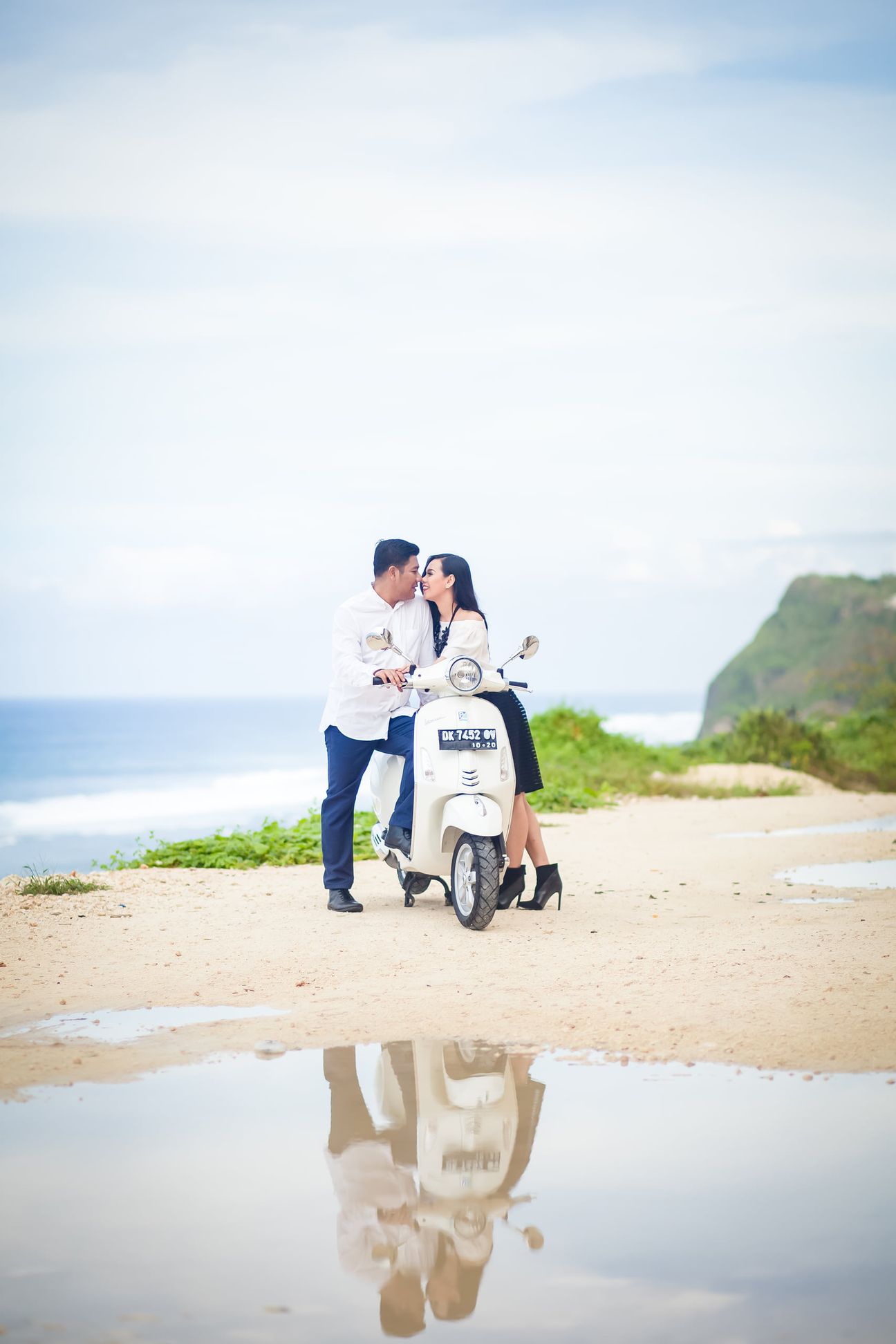 A couple stand together during a small ceremony on a beach