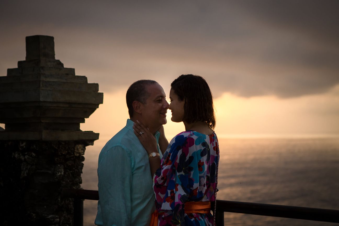 A couple share a quiet moment overlooking the sea at sunset