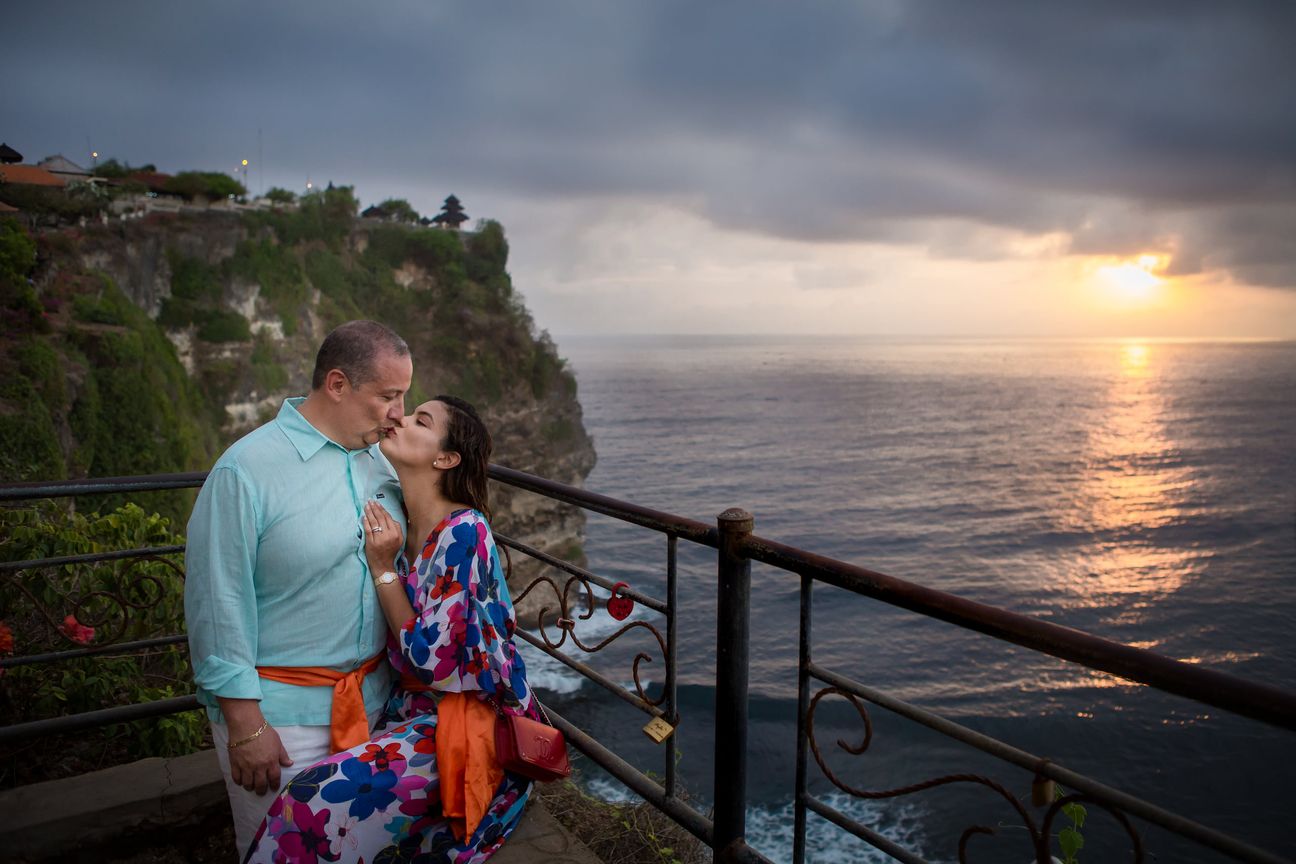 A couple share a quiet moment overlooking the sea at sunset