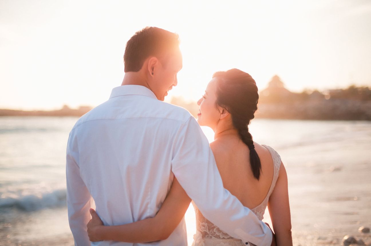 A bride and groom embrace along a wooden boardwalk through leafy mangroves