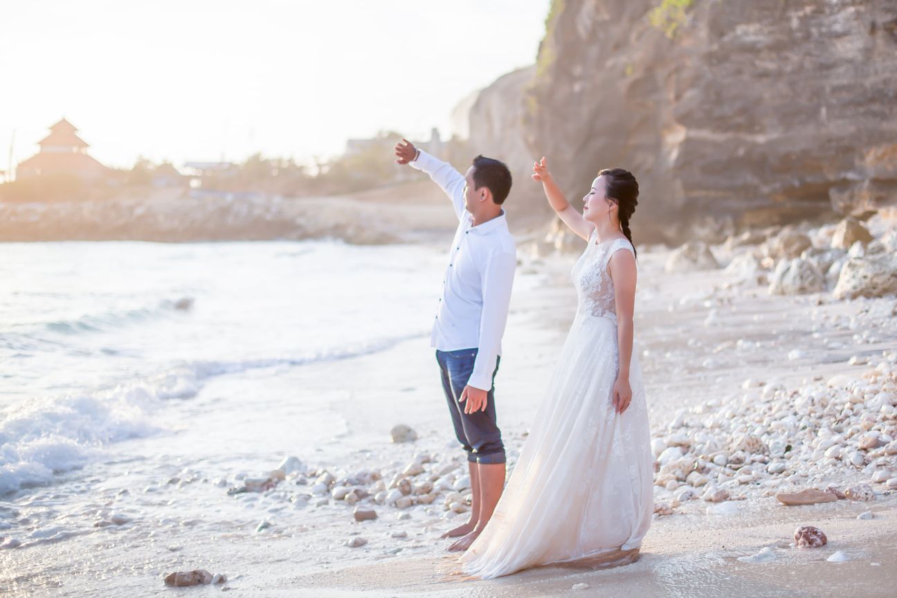 A bride and groom embrace along a wooden boardwalk through leafy mangroves