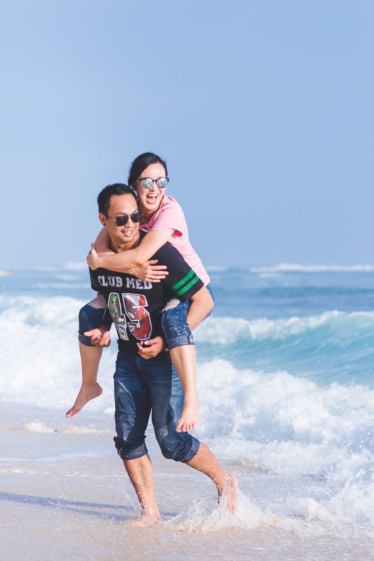 A laughing couple play together in the breaking ocean surf