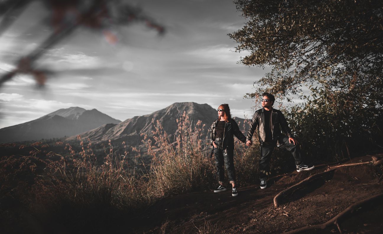 A couple pause with a motorcycle against a mountain landscape