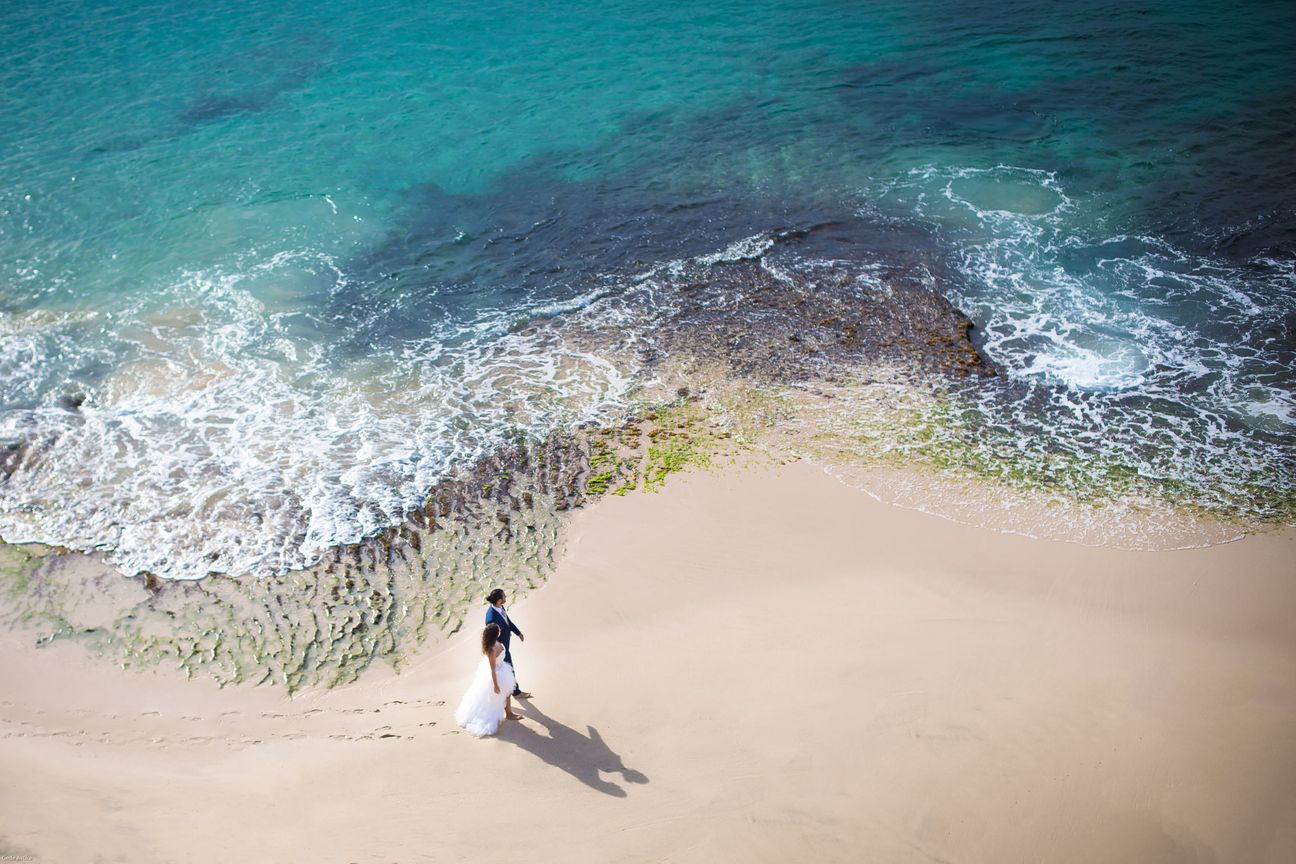 A couple look across the coastline from a high viewpoint