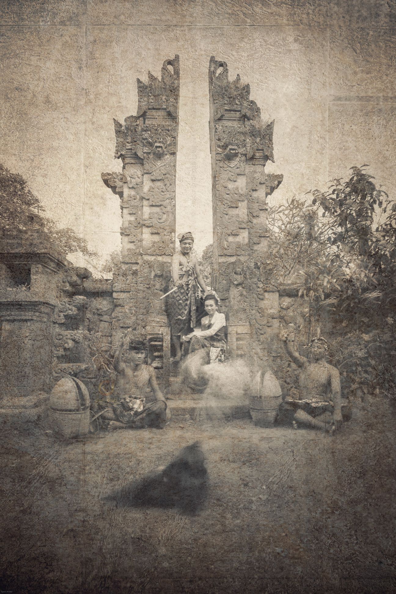 A royal Balinese wedding couple seated with their ceremonial entourage in vintage sepia tones