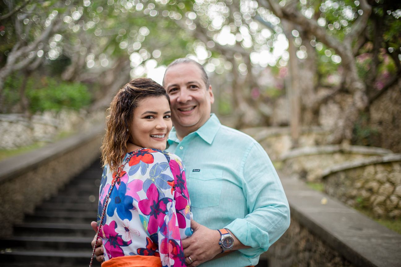 A smiling couple embrace above a rocky Bali coastline