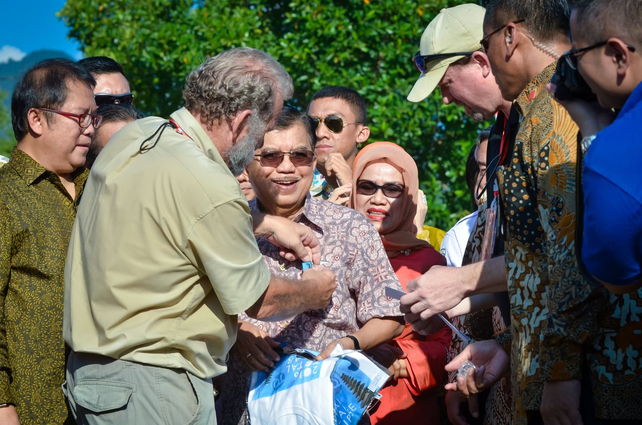 A tour leader leans in to greet guests gathered on the grass before the eclipse