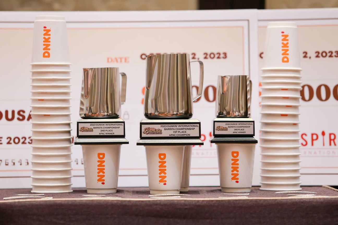 Three milk pitchers mounted as trophies between stacks of paper cups