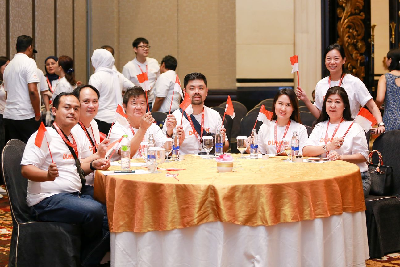 Guests around a gold-clothed table hold up flags for the camera