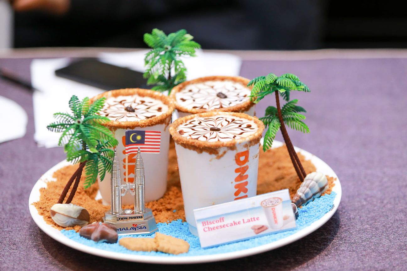 Three iced coffees dressed with toy palm trees and biscuit sand on a white plate
