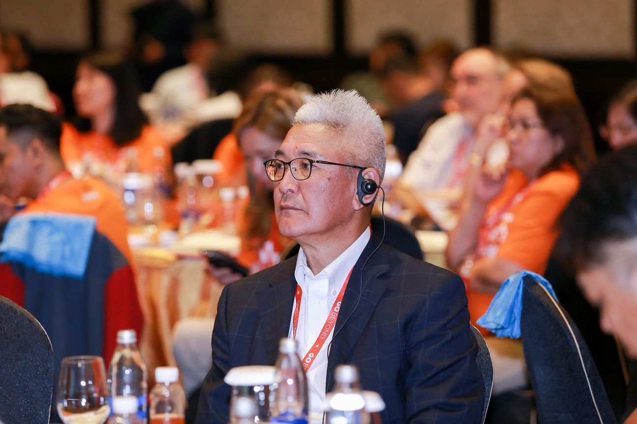 A delegate with an interpreter’s earpiece watches the stage from his table