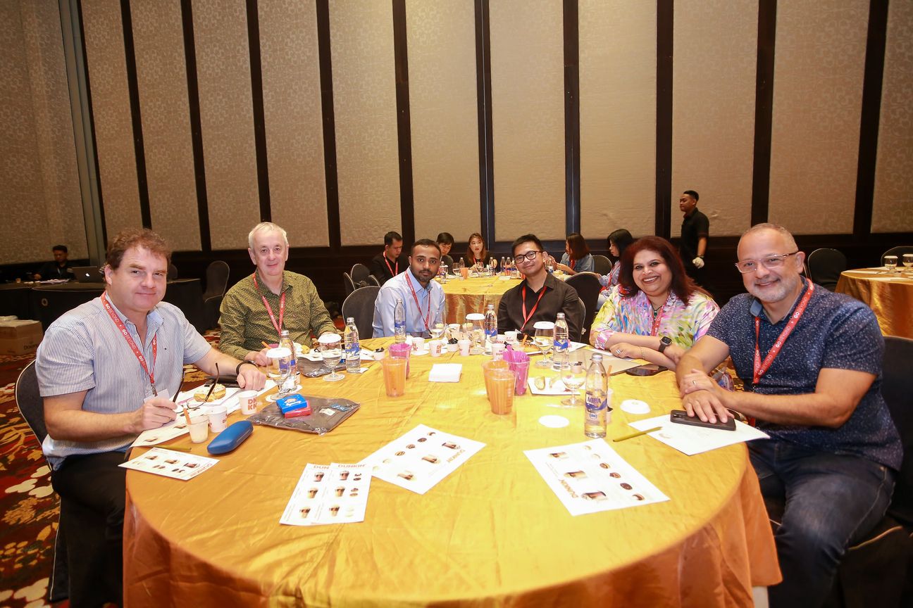 Six delegates seated around a gold table with tasting notes in front of them