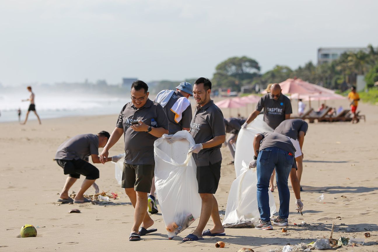 Volunteers work along the tideline filling white sacks with litter