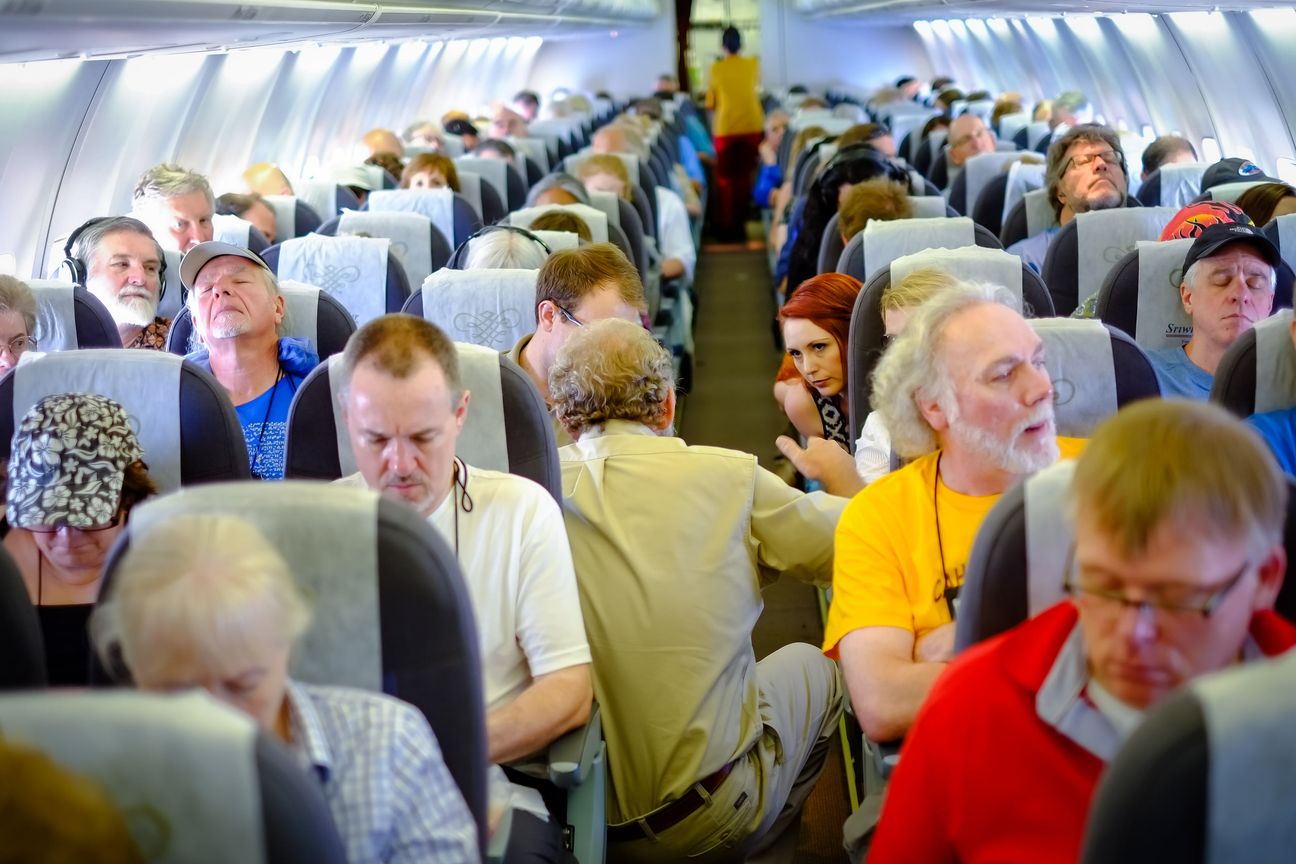 A full cabin of travellers reading and dozing on a chartered flight