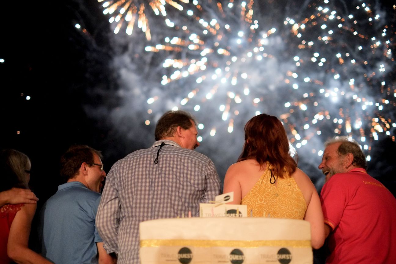 Guests seen from behind, their faces lit, as fireworks fill the sky above them