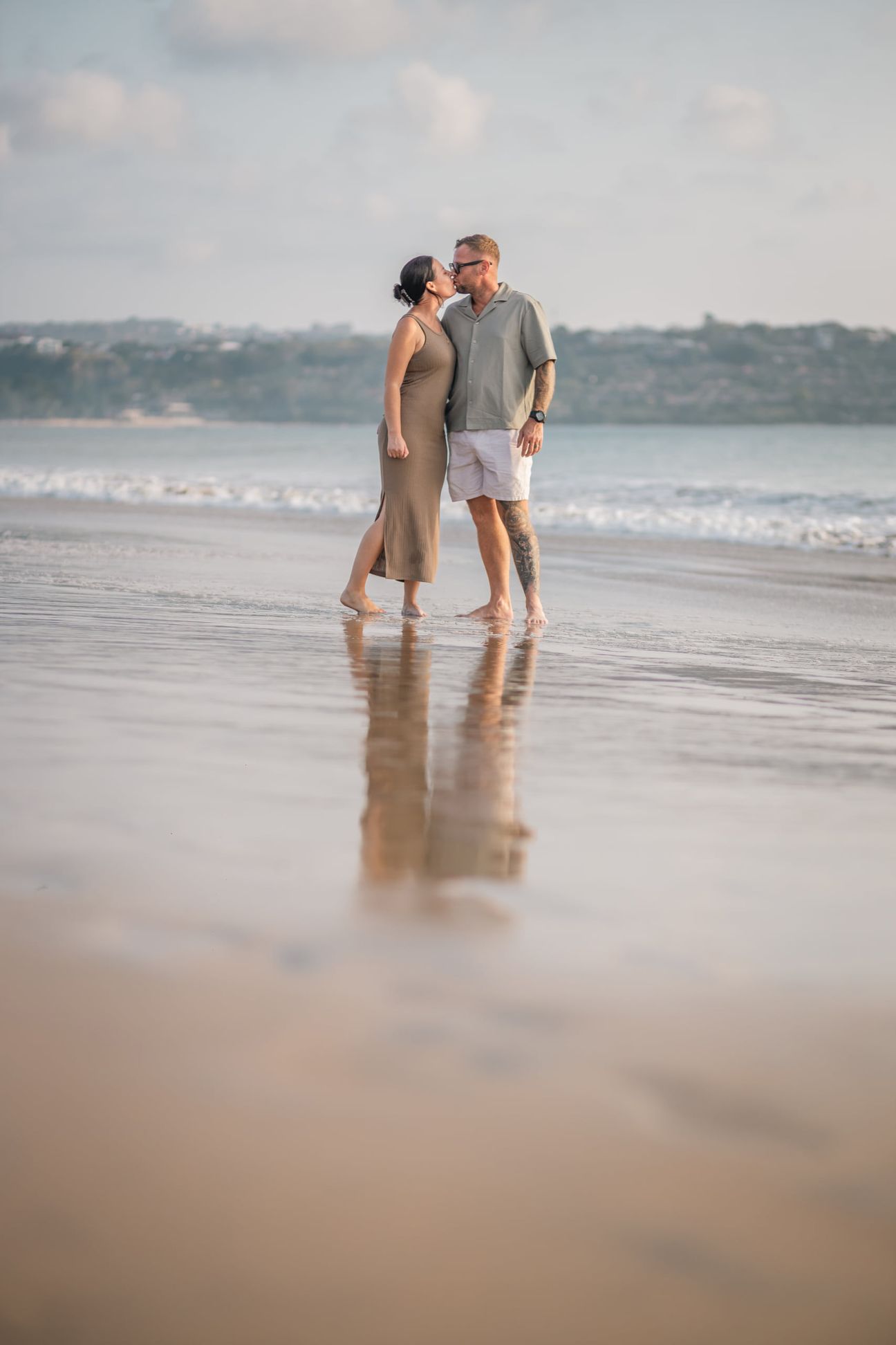 Two adults walk hand in hand along the waterline