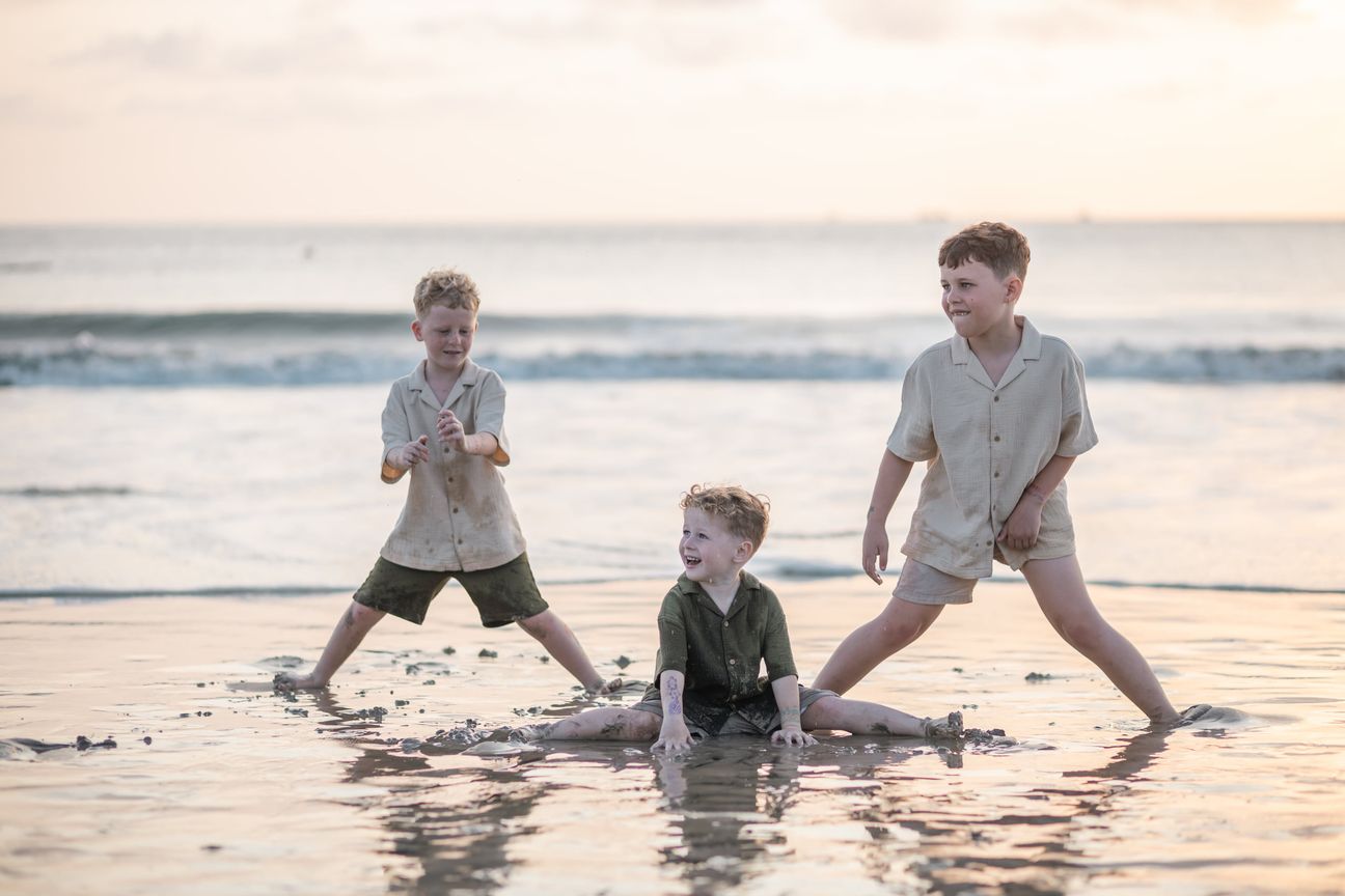 Children play together in the shallow sea at sunset