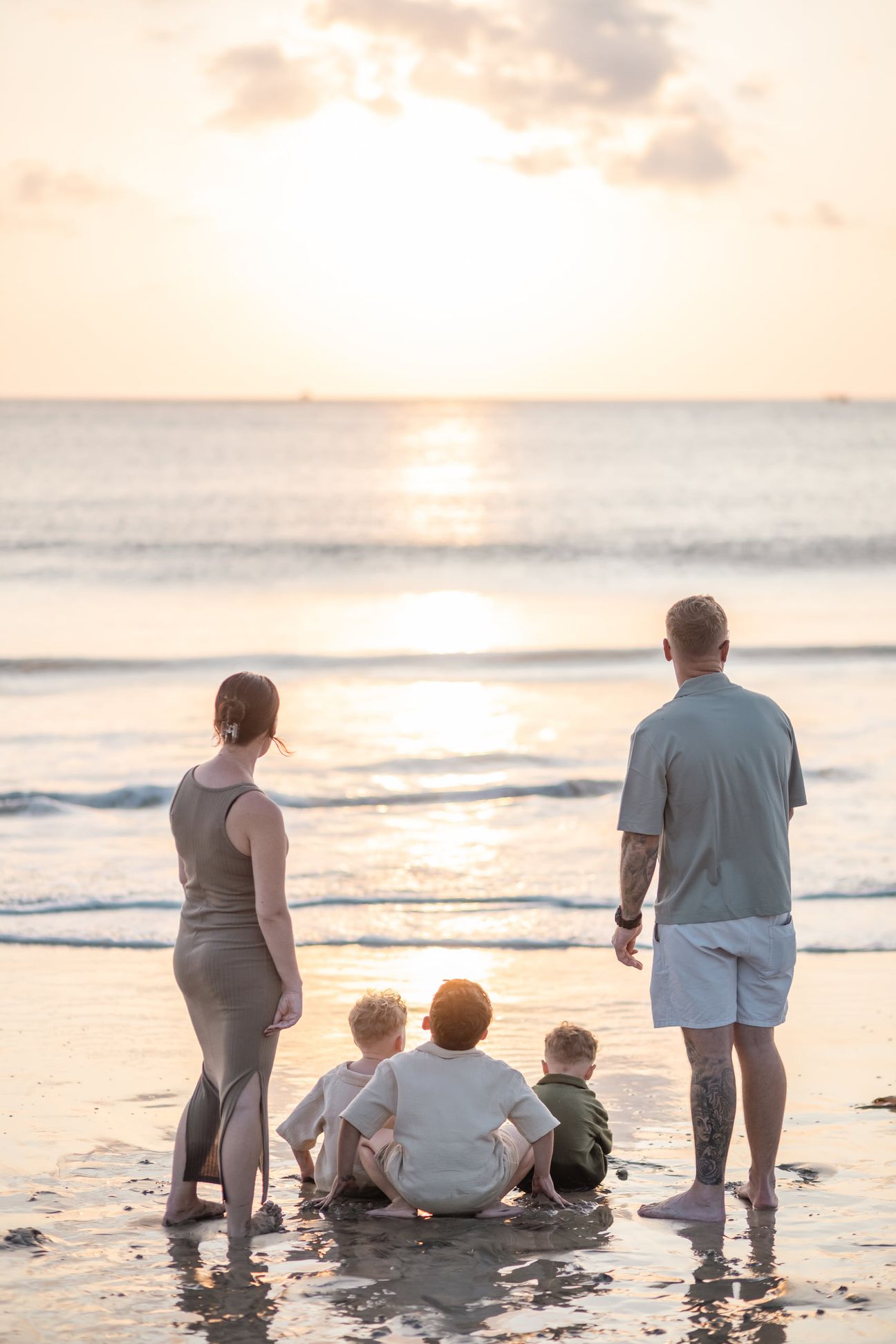 Children play together in the shallow sea at sunset