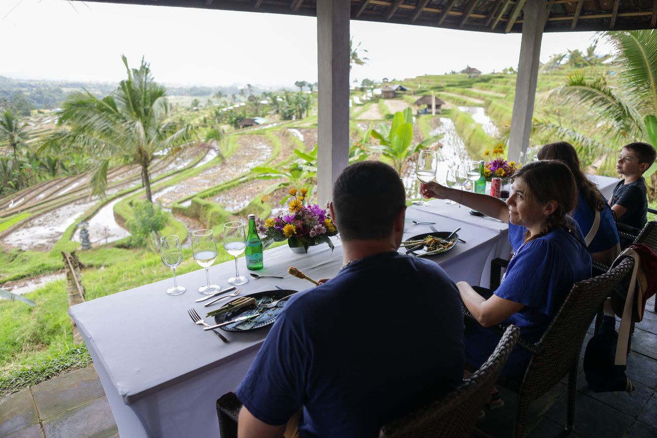 A family sit down to lunch in an open pavilion above green rice terraces