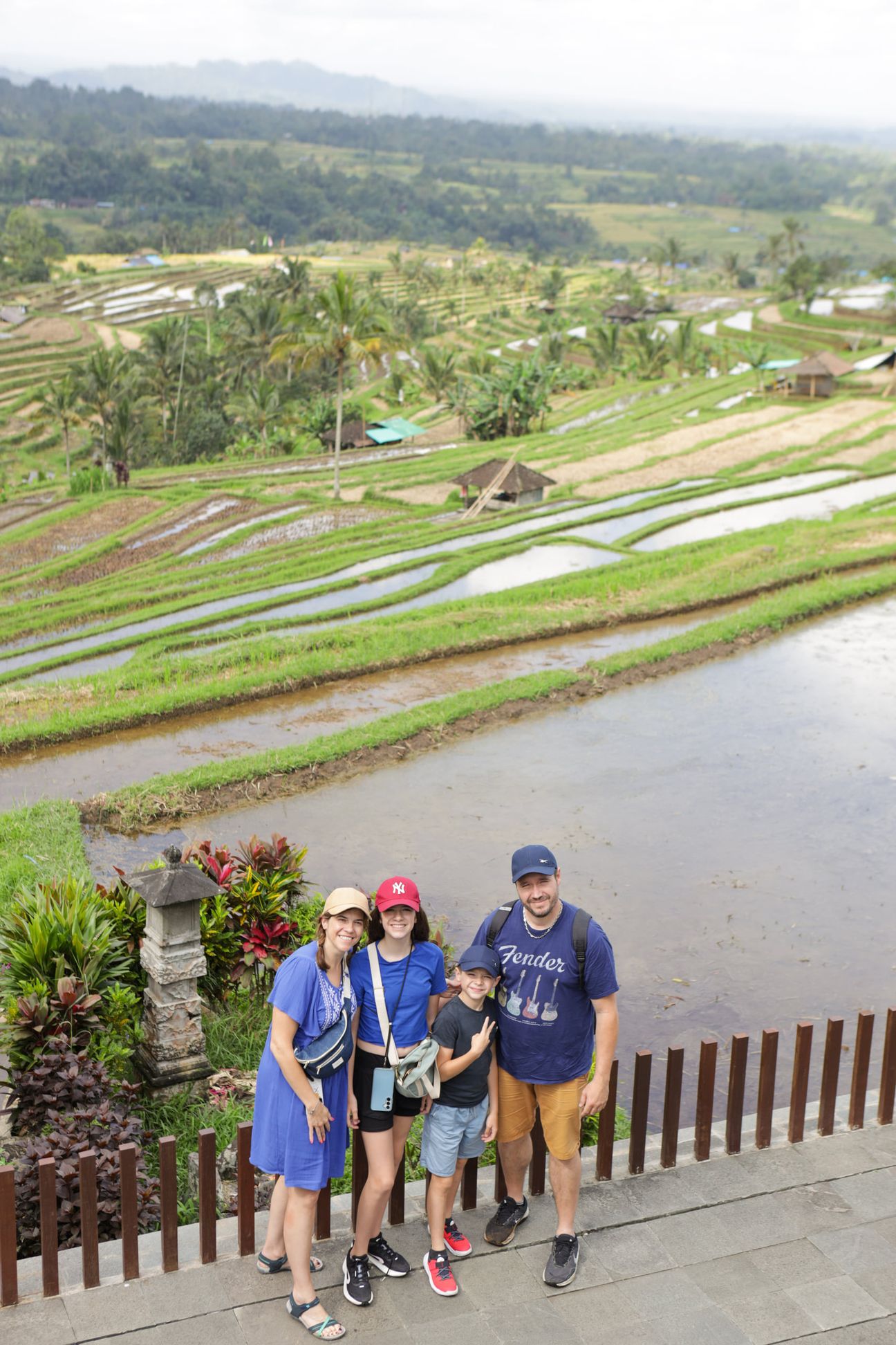 A family of four smile from a dining table overlooking green rice terraces