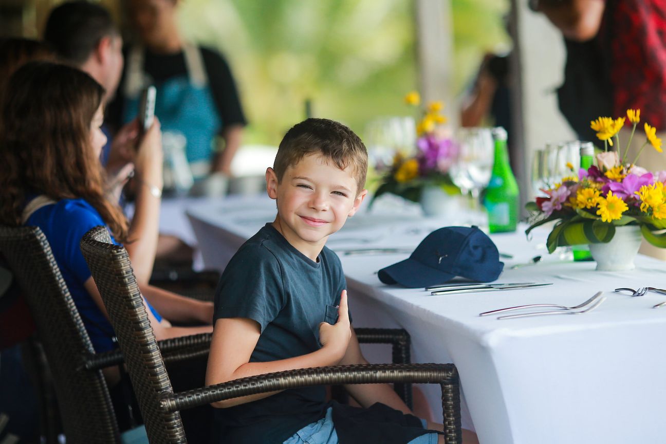 A young boy and his family share relaxed moments at a shaded garden table
