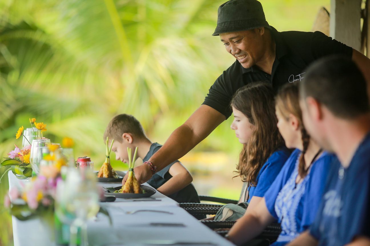A young boy and his family share relaxed moments at a shaded garden table