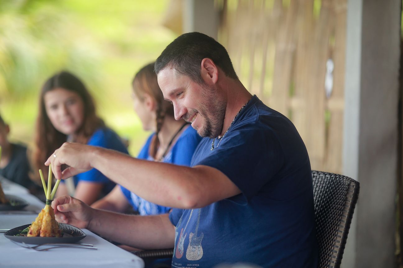 A young boy and his family share relaxed moments at a shaded garden table