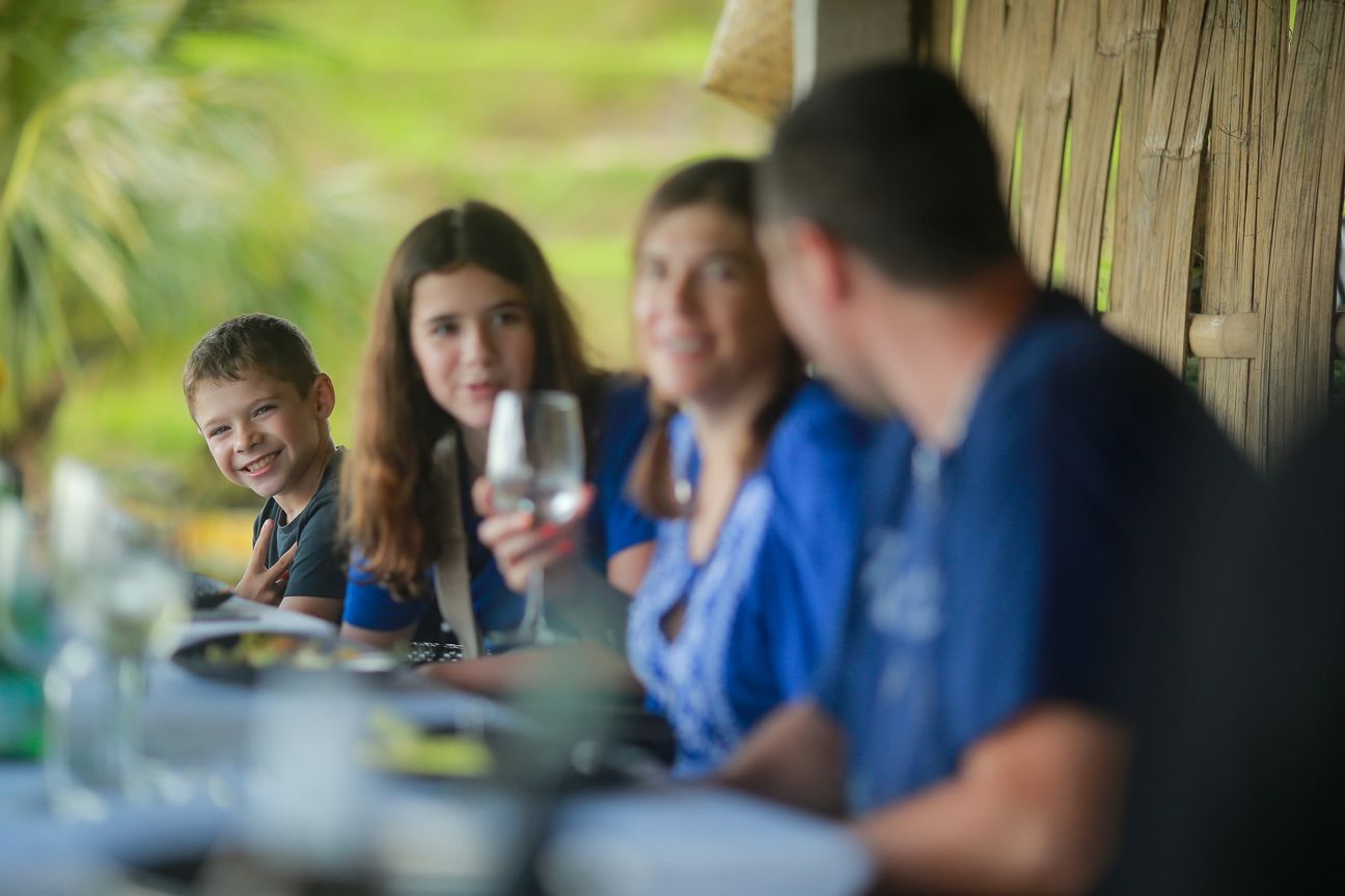 A young boy and his family share relaxed moments at a shaded garden table