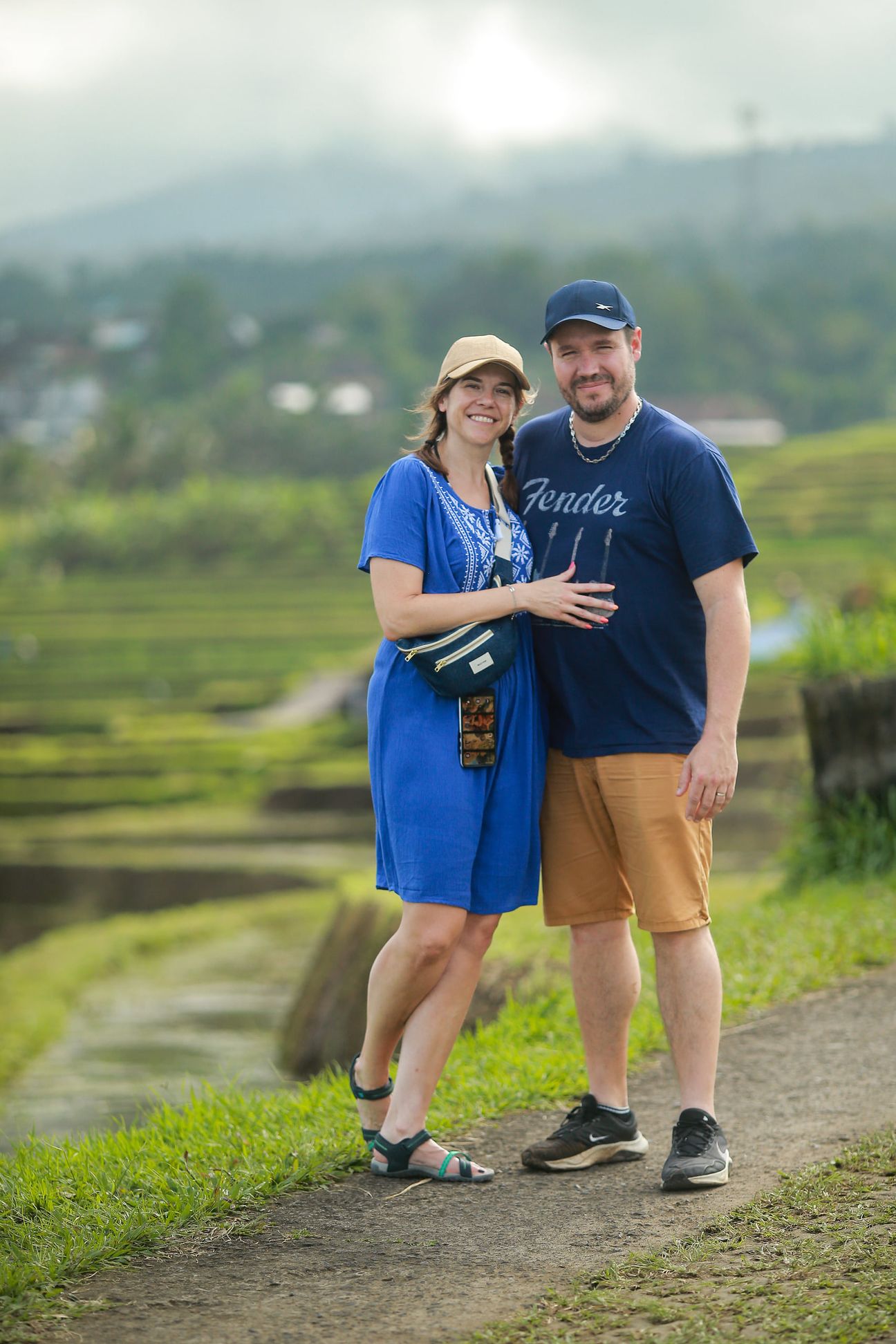 A couple in blue stand arm in arm on a path through the rice terraces