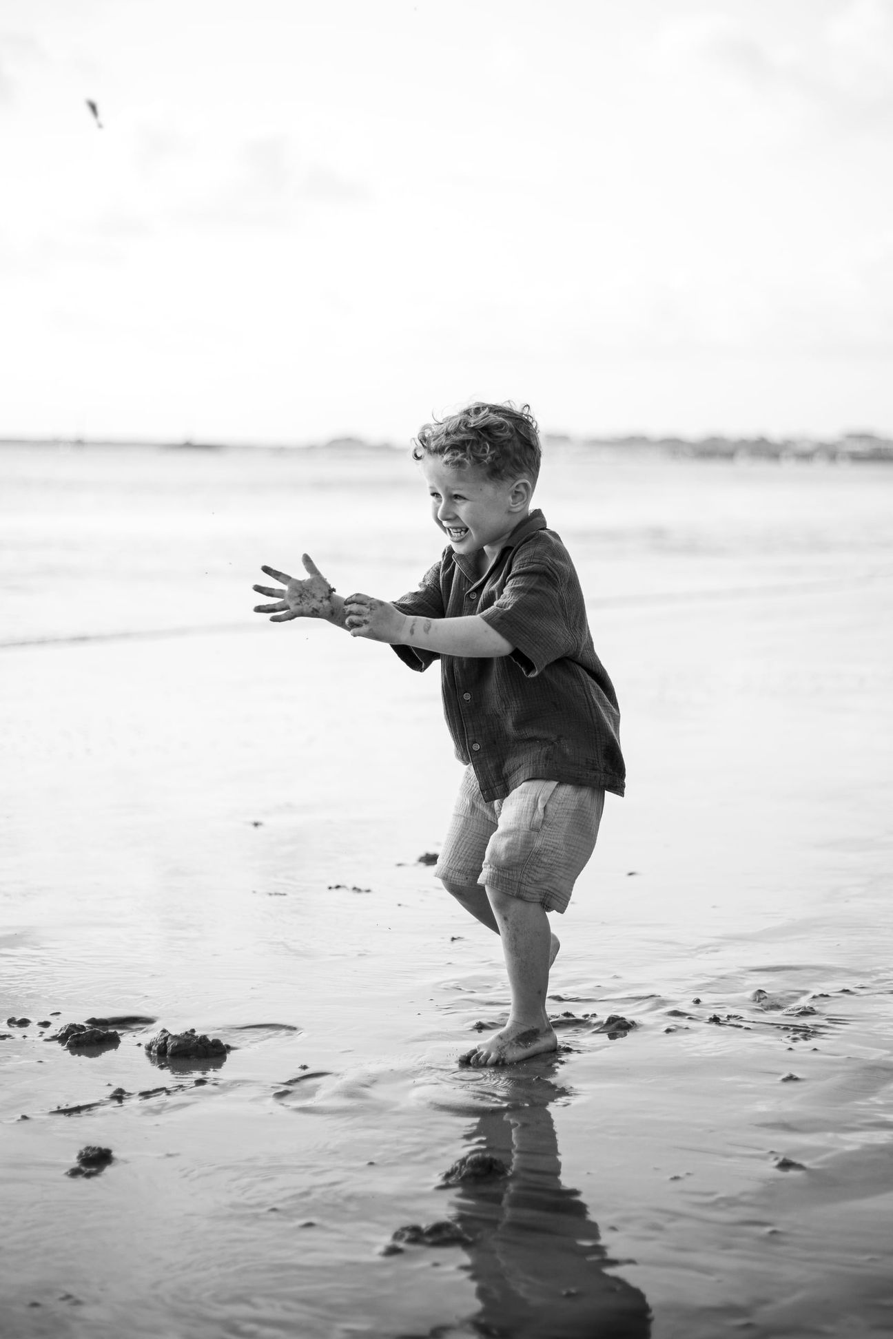 Young children laugh and play together on a bright beach