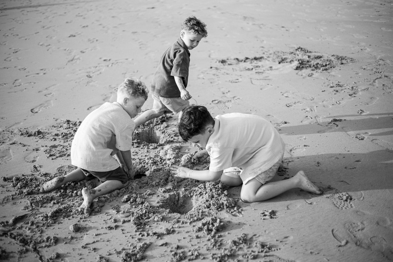 Young children laugh and play together on a bright beach