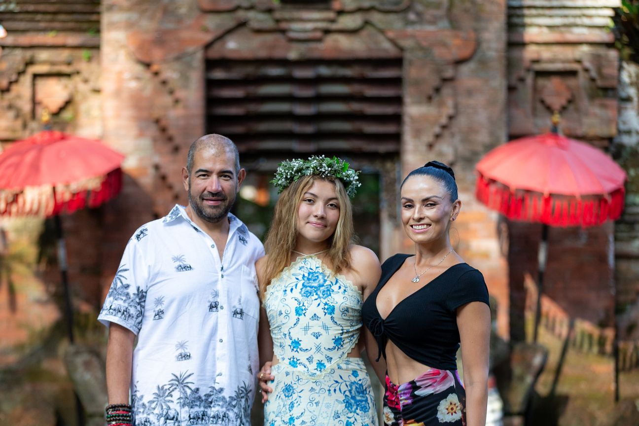 A family group pose together at a traditional Balinese entrance
