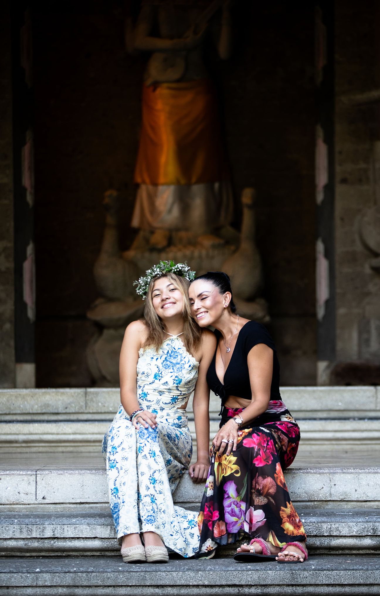A mother and her adult daughters share a relaxed portrait in a garden