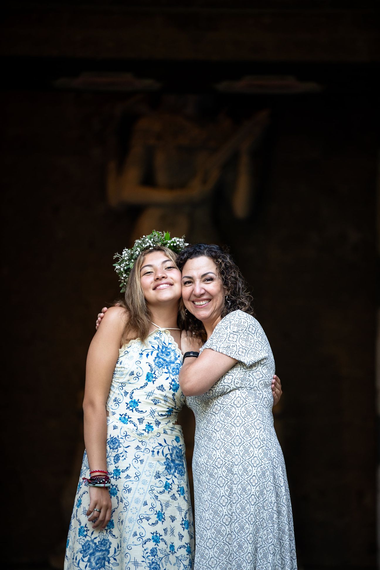 A mother and her adult daughters share a relaxed portrait in a garden