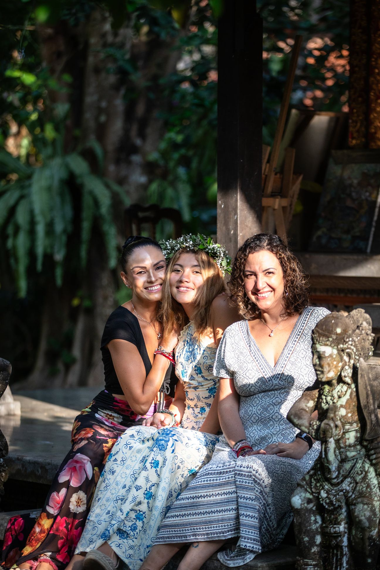 A mother and her adult daughters share a relaxed portrait in a garden