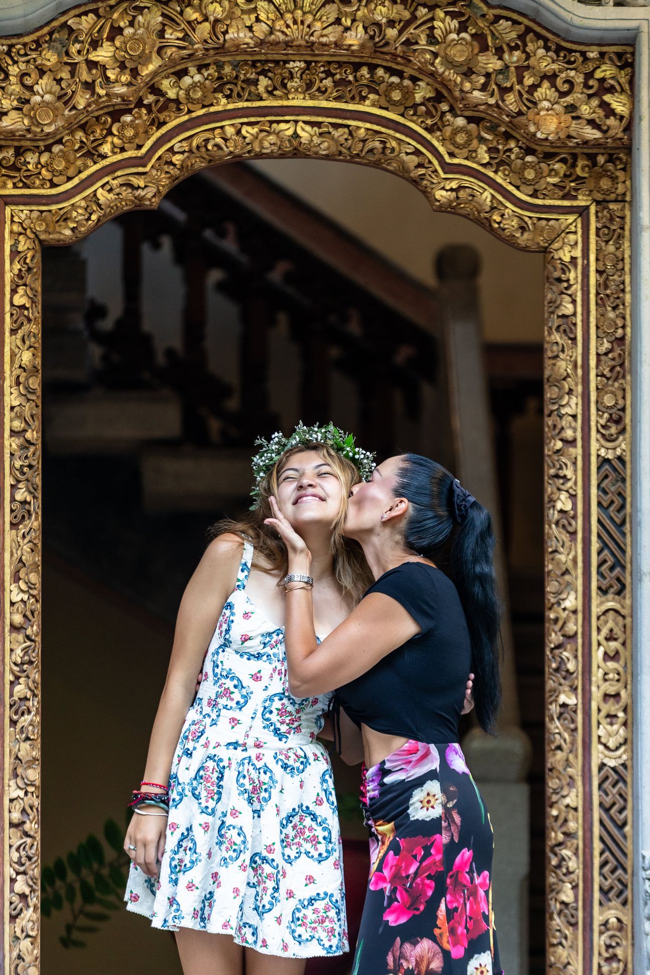 A mother and her adult daughters share a relaxed portrait in a garden