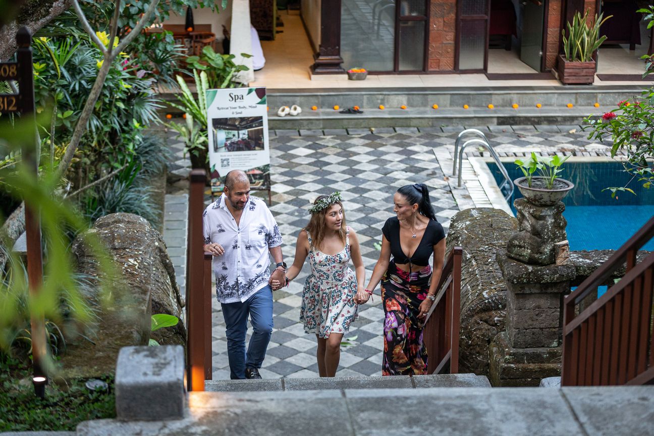 A family climb stone steps through a tropical garden