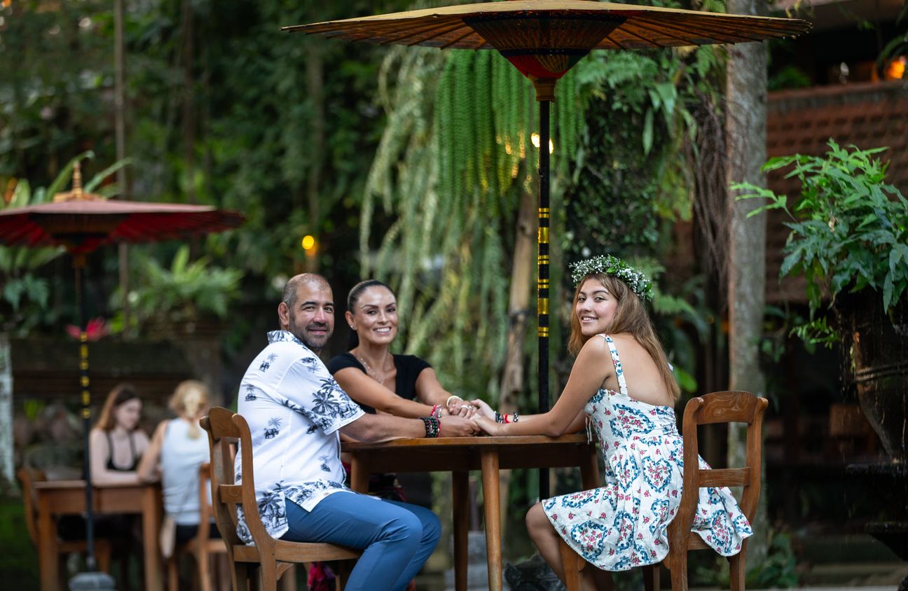 A family laugh together around a shaded garden table