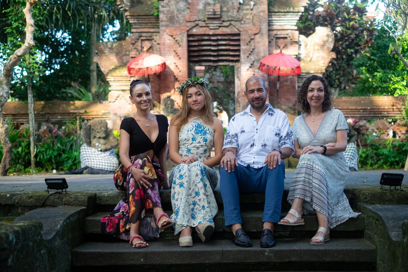 A family group sit together in a Balinese garden